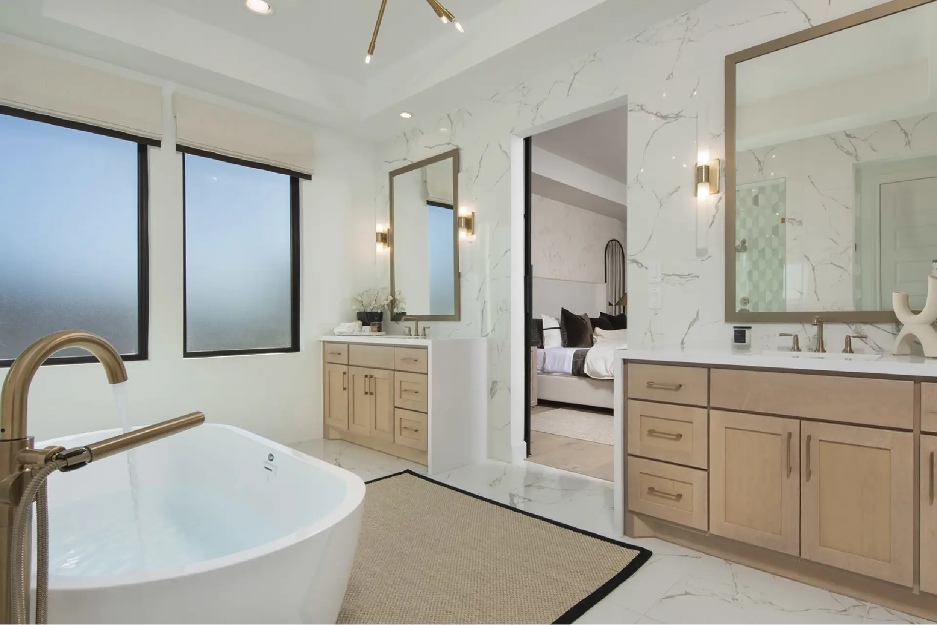 Fort Wayne Home Remodeling: Luxury bathroom remodel in Fort Wayne by Home Enterprises Inc., featuring a freestanding tub, light wood custom vanity, double sinks with elegant gold faucets, and stone floor tiles.